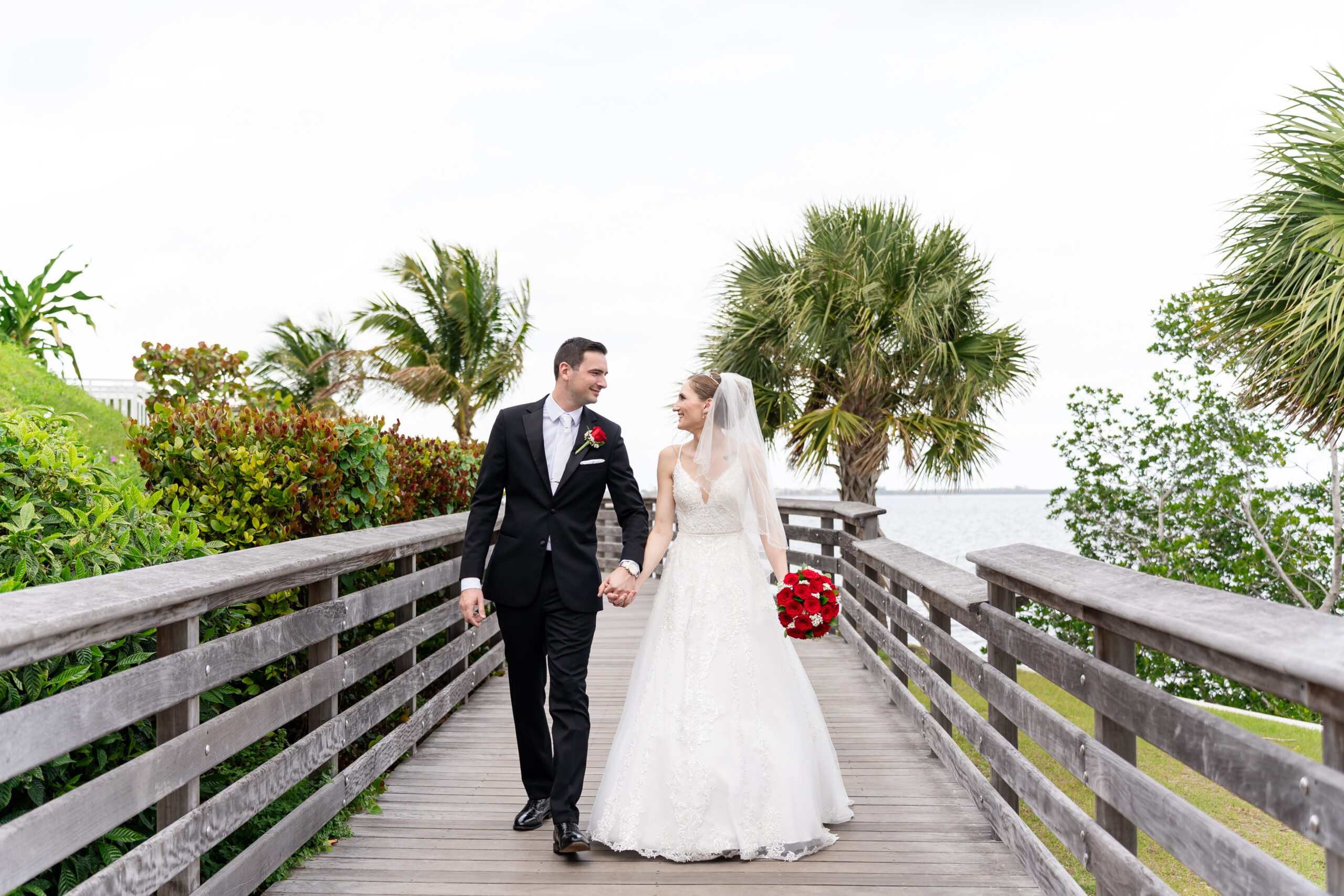 Cinematic wedding portrait at The Mansion at Tuckahoe featuring a couple on a waterfront boardwalk with palm trees and a view of the Indian River by Dear Magnolia Films.